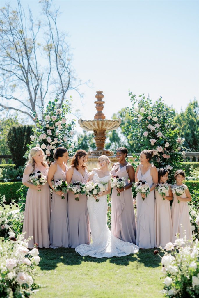 Bride and bridesmaids in blush mauve bridesmaid dresses holding bouquets