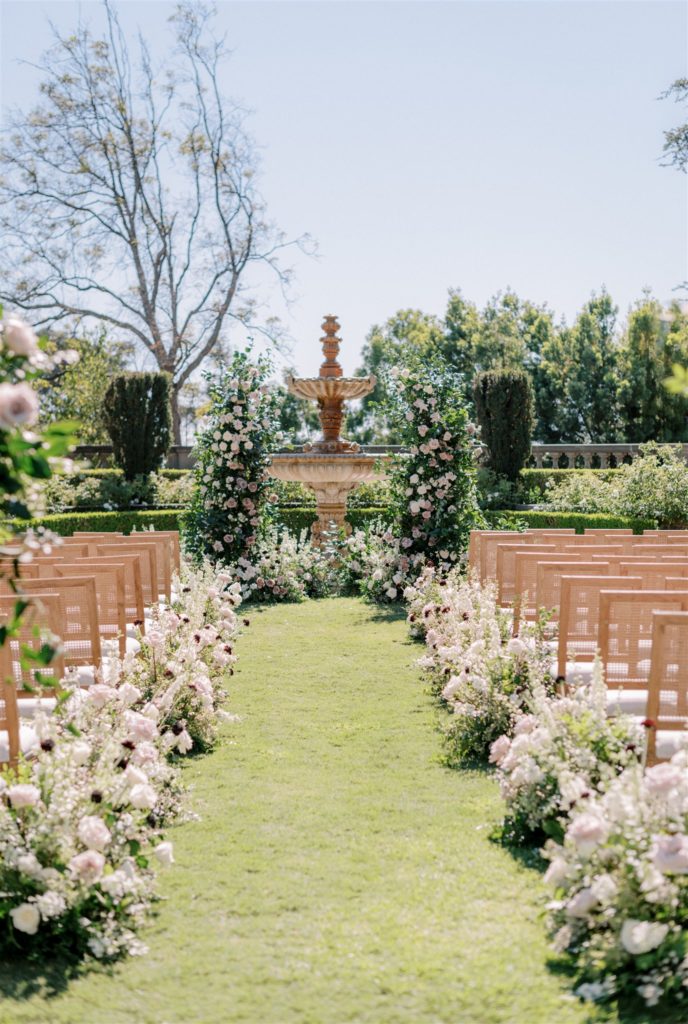 Lush floral aisle blush and white with wooden ceremony chairs and floral arch
