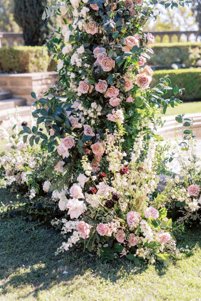 blush and mauve growing garden style floral installation with greenery and pops of plum